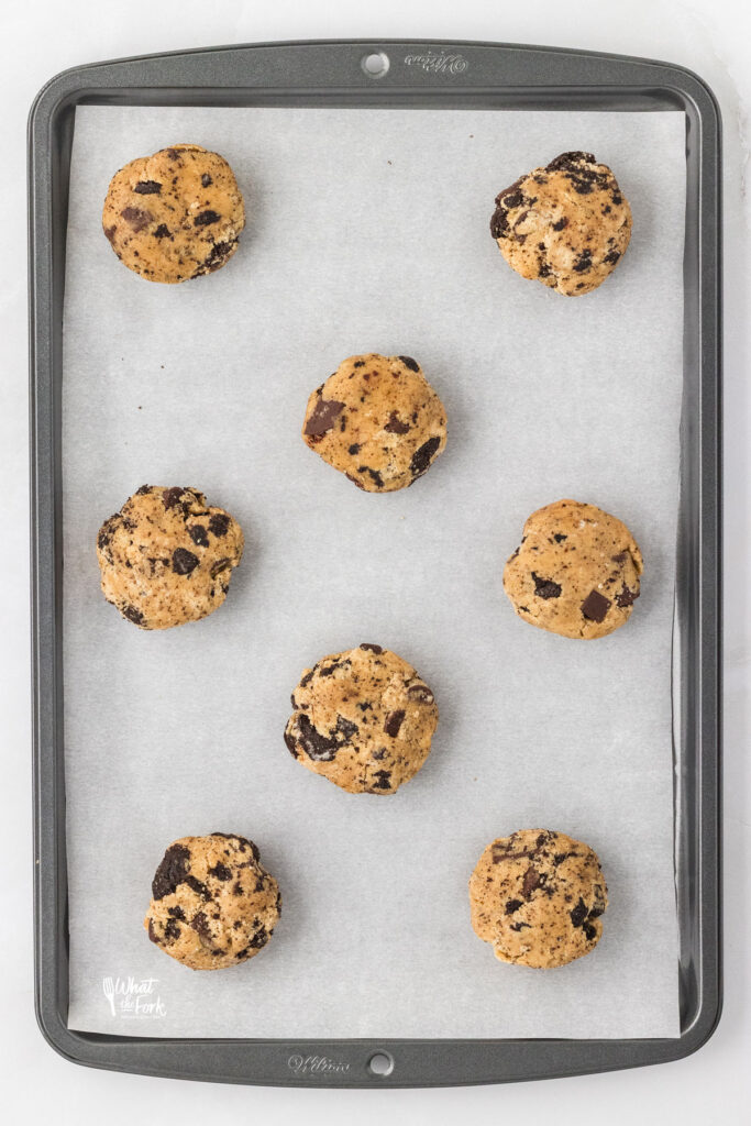Gluten Free Oreo Chocolate Chip Cookie dough portioned out on a silver baking sheet lined with white parchment paper ready to be baked