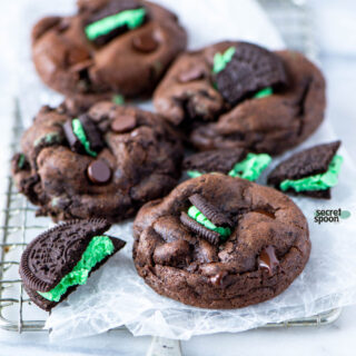 Gluten Free Double Chocolate Mint Oreo Cookies on a wax paper lined mini metal rack with broken gluten free mint Oreos around the cookies